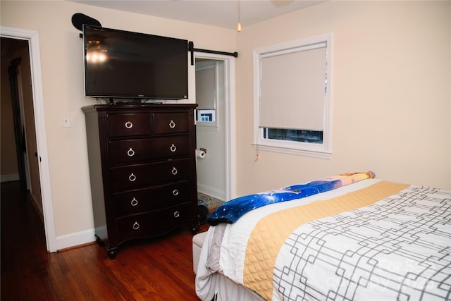 bedroom with a barn door and dark hardwood / wood-style floors