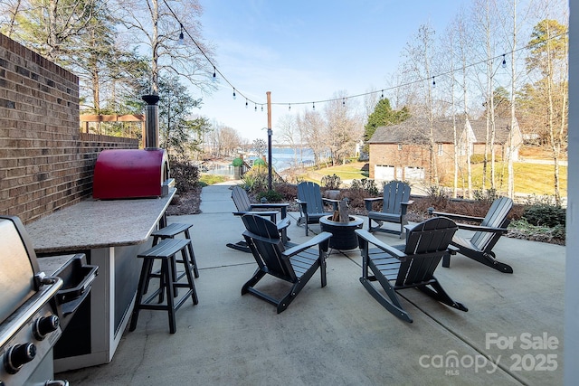 view of patio / terrace featuring a bar, grilling area, and an outdoor fire pit