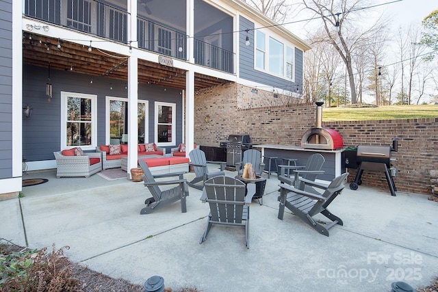 view of patio / terrace featuring grilling area, a balcony, and an outdoor living space with a fireplace