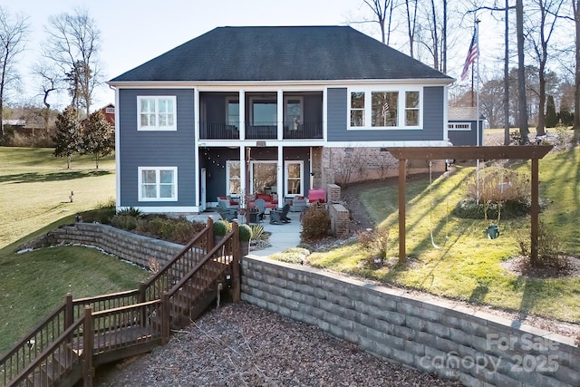 rear view of property with a yard, a sunroom, and a patio