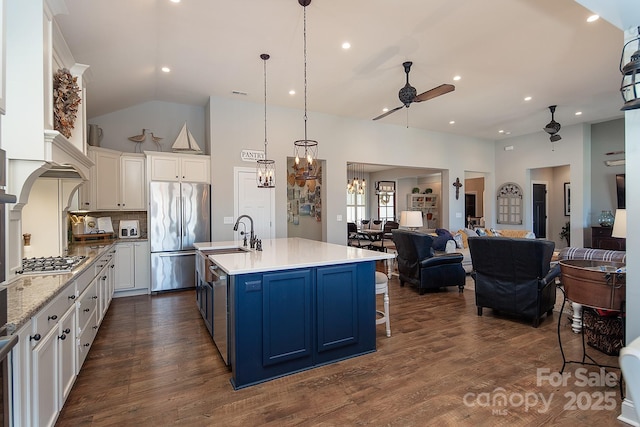 kitchen with blue cabinetry, white cabinetry, appliances with stainless steel finishes, and an island with sink