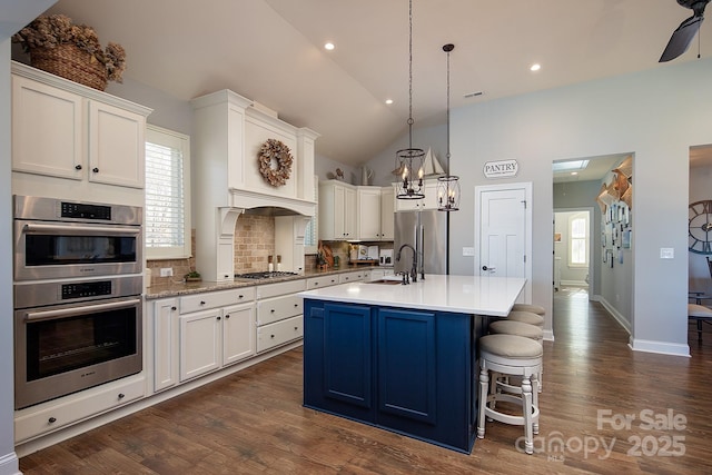 kitchen with appliances with stainless steel finishes, an island with sink, and white cabinets