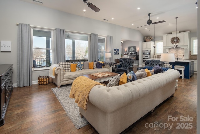 living room with dark hardwood / wood-style flooring, ceiling fan, lofted ceiling, and a healthy amount of sunlight