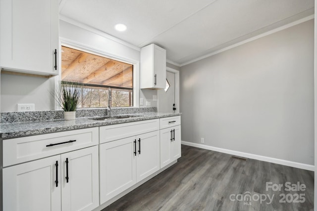 kitchen featuring sink, white cabinets, dark hardwood / wood-style flooring, light stone counters, and crown molding