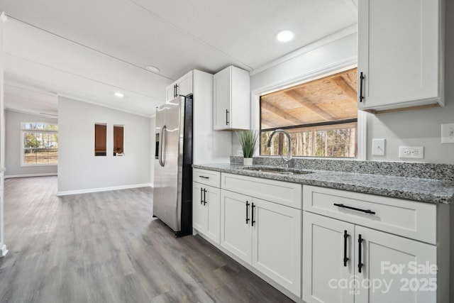 kitchen featuring stainless steel refrigerator with ice dispenser, lofted ceiling, sink, light stone countertops, and white cabinets