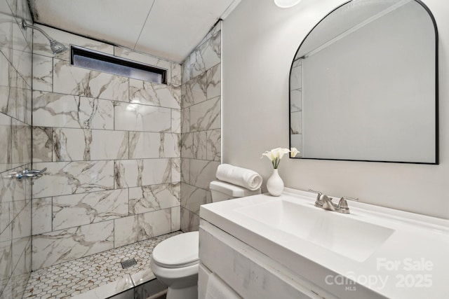 bathroom featuring vanity, tiled shower, and toilet