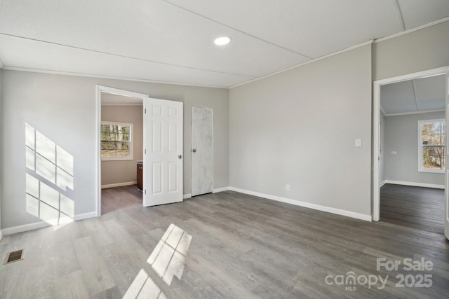 empty room featuring crown molding, wood-type flooring, and a wealth of natural light