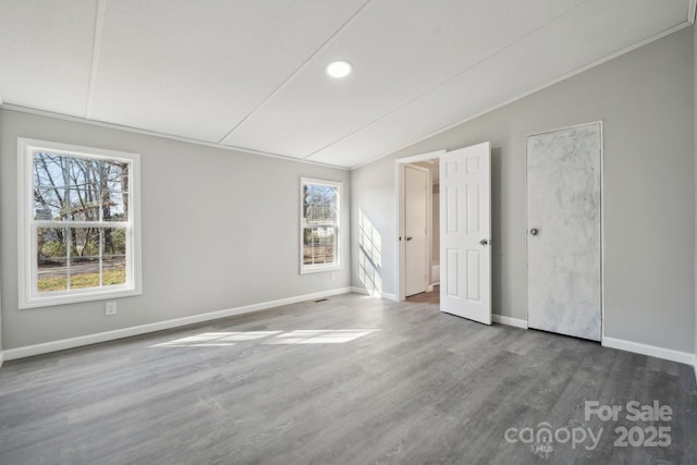 unfurnished room featuring dark wood-type flooring, vaulted ceiling, and ornamental molding