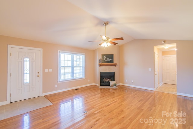 unfurnished living room with ceiling fan, lofted ceiling, a fireplace, and light hardwood / wood-style flooring