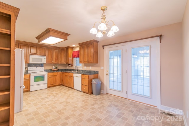 kitchen featuring sink, a notable chandelier, white appliances, and decorative light fixtures