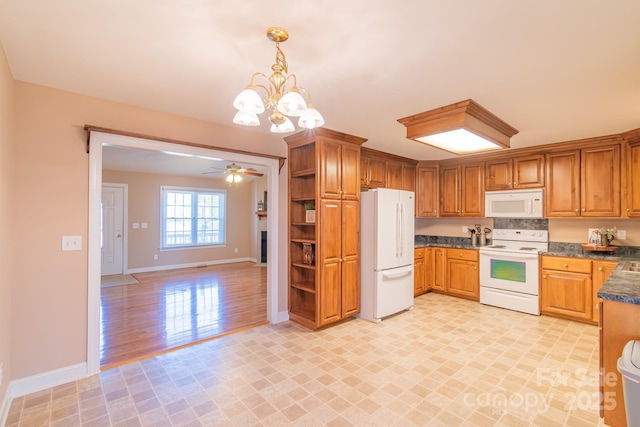 kitchen featuring pendant lighting, white appliances, and ceiling fan with notable chandelier