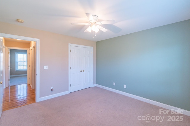 unfurnished bedroom featuring light colored carpet, ceiling fan, and a closet