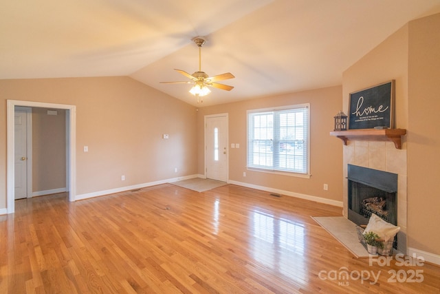 unfurnished living room featuring ceiling fan, light wood-style flooring, baseboards, vaulted ceiling, and a tiled fireplace