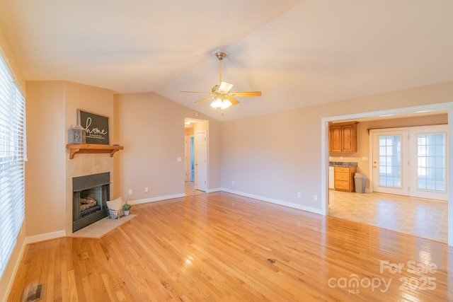 unfurnished living room featuring plenty of natural light, visible vents, a fireplace, and light wood finished floors