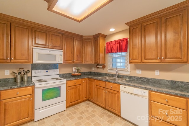 kitchen with brown cabinets, dark countertops, recessed lighting, a sink, and white appliances