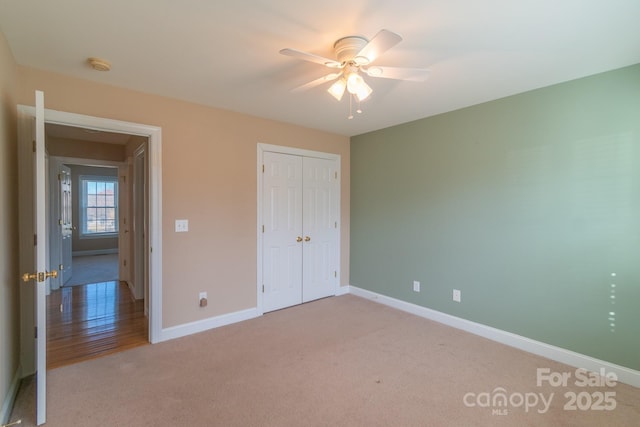 unfurnished bedroom featuring baseboards, a closet, a ceiling fan, and light colored carpet