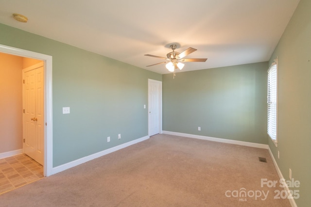 unfurnished room with light carpet, ceiling fan, visible vents, and baseboards