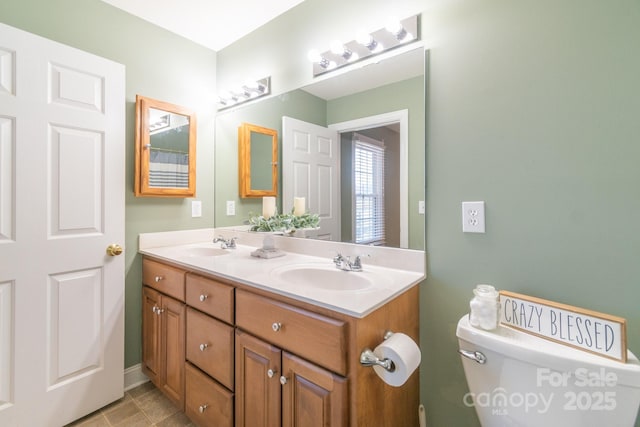 bathroom with double vanity, a sink, and toilet