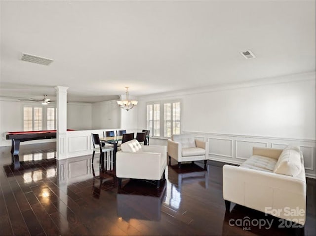 living room with crown molding, billiards, dark hardwood / wood-style flooring, ceiling fan with notable chandelier, and ornate columns