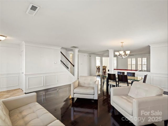 living room with decorative columns, ornamental molding, dark hardwood / wood-style floors, and a chandelier