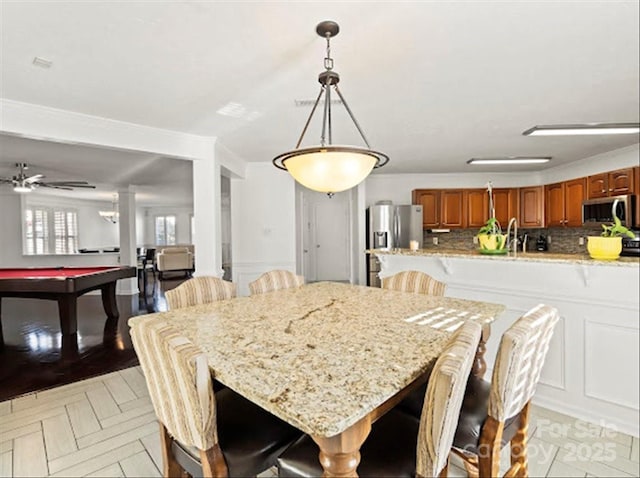 dining room with pool table, light parquet flooring, and decorative columns