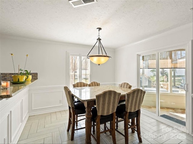 dining area with light parquet floors, crown molding, and a textured ceiling