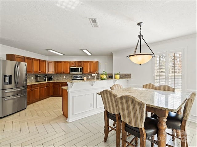 kitchen featuring pendant lighting, sink, stainless steel appliances, a center island with sink, and decorative backsplash