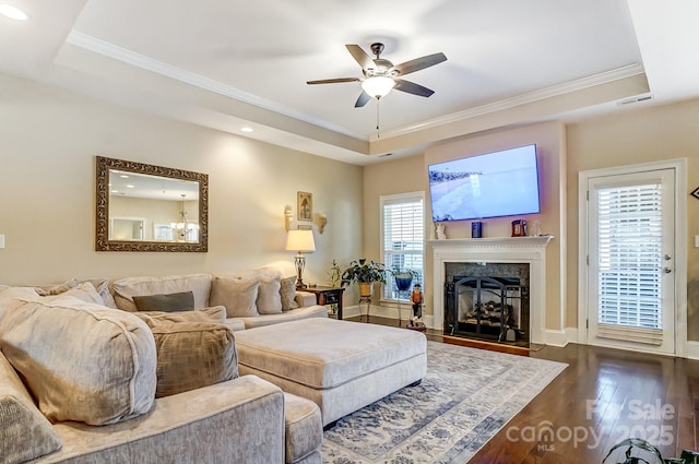 living room with ornamental molding, dark hardwood / wood-style floors, and a tray ceiling