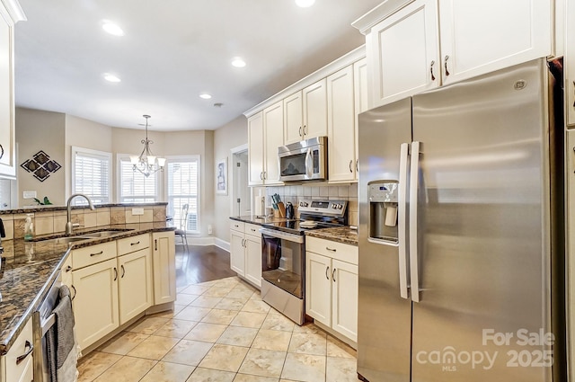 kitchen featuring dark stone countertops, appliances with stainless steel finishes, sink, and pendant lighting