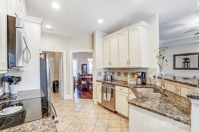 kitchen with white cabinetry, stainless steel appliances, sink, and dark stone counters