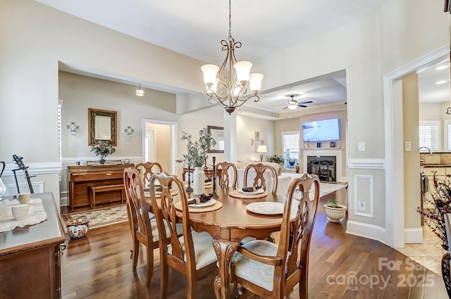 dining area with wood-type flooring, sink, and ceiling fan with notable chandelier