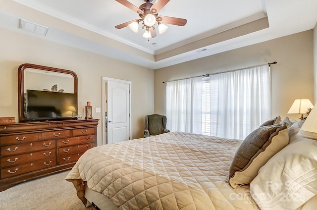 bedroom featuring ceiling fan, ornamental molding, a tray ceiling, and light carpet