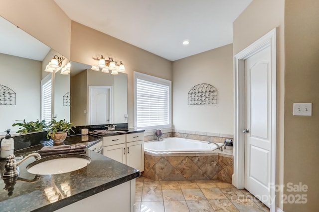 bathroom with tiled tub and vanity