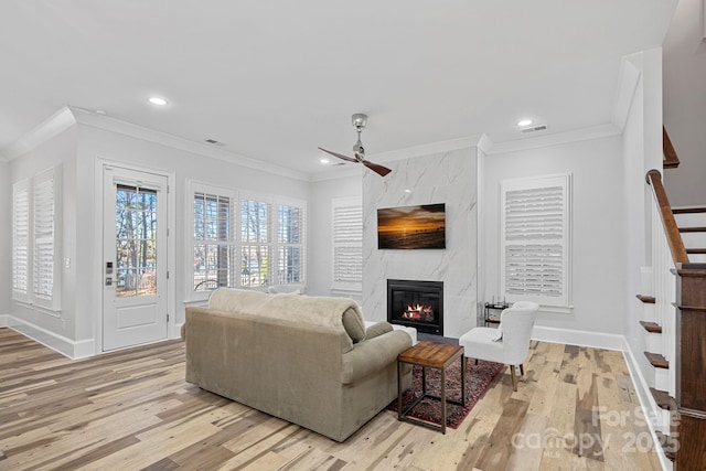 living room with ornamental molding, a fireplace, and light hardwood / wood-style flooring