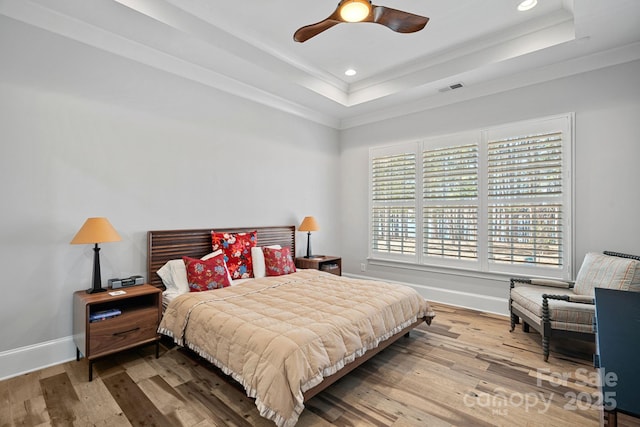 bedroom with ornamental molding, a raised ceiling, and hardwood / wood-style floors