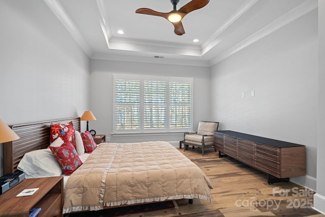 bedroom featuring hardwood / wood-style flooring, ceiling fan, a tray ceiling, and crown molding