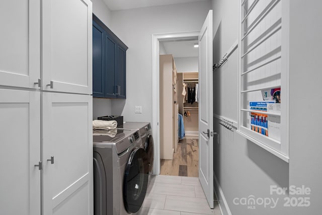 clothes washing area with cabinets and washing machine and dryer