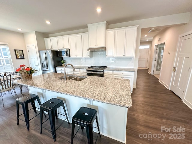kitchen with white cabinetry, sink, stainless steel appliances, and a kitchen bar