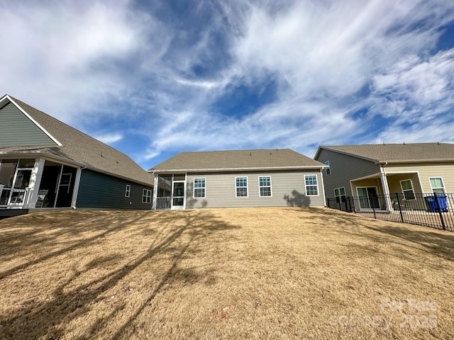 rear view of property with a lawn and a sunroom