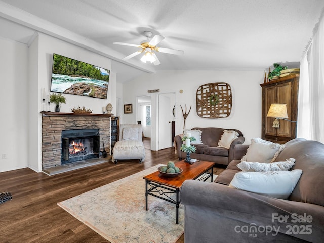 living room featuring a stone fireplace, dark hardwood / wood-style floors, vaulted ceiling with beams, and ceiling fan