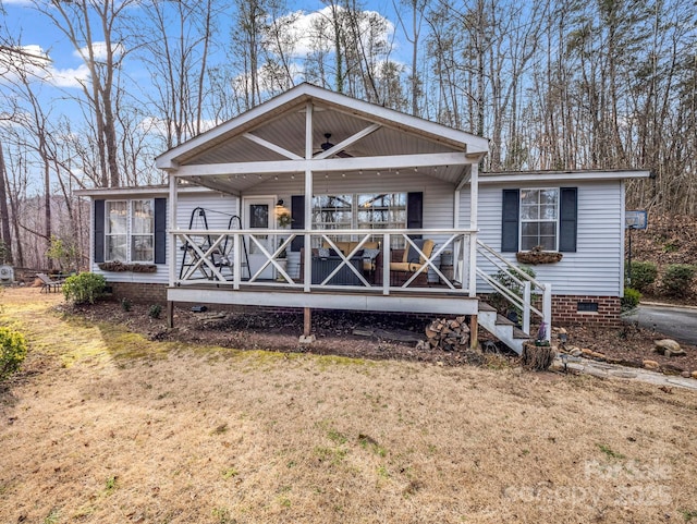 back of property with a yard, ceiling fan, and a porch