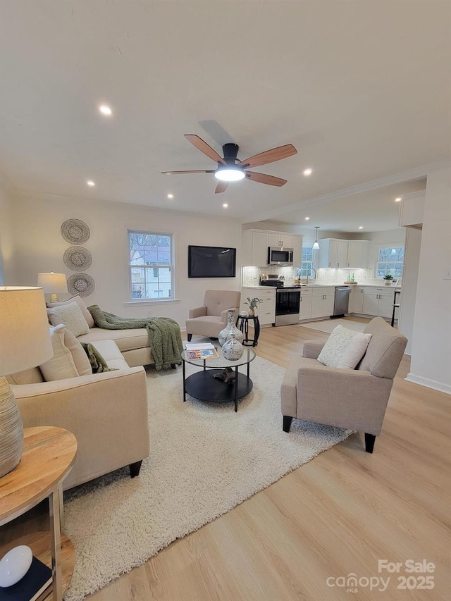 living room with vaulted ceiling, ceiling fan, and light wood-type flooring