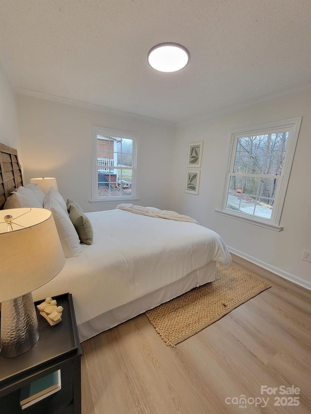 bedroom with crown molding, hardwood / wood-style floors, and a textured ceiling