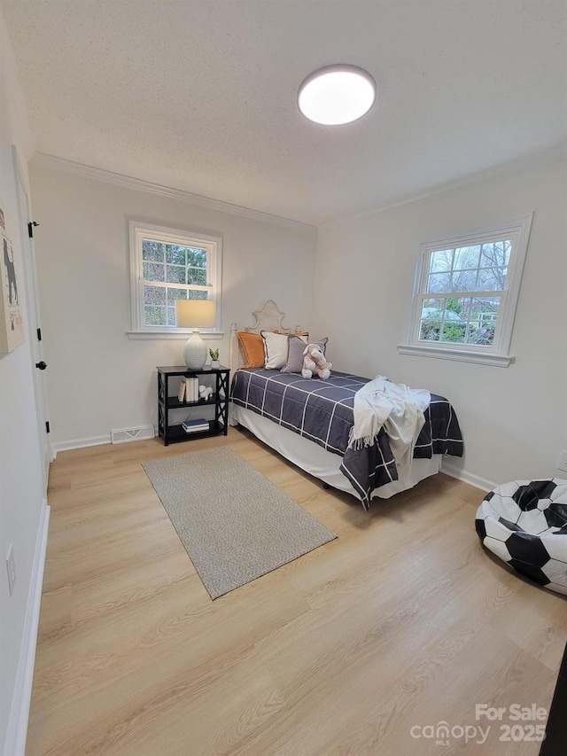 bedroom with multiple windows, ornamental molding, and hardwood / wood-style floors