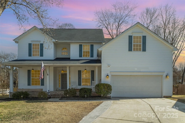 view of front facade featuring a porch, a front lawn, driveway, and an attached garage