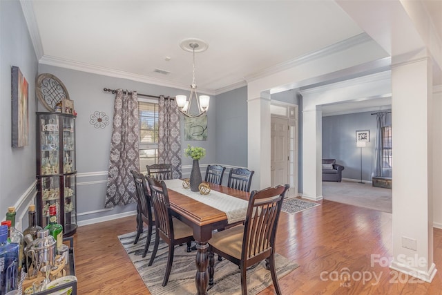 dining area with ornamental molding, dark wood-style flooring, visible vents, and an inviting chandelier