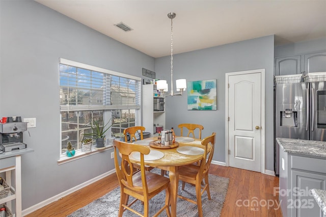 dining area featuring dark wood-style floors, visible vents, baseboards, and an inviting chandelier