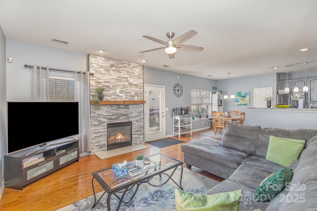 living area featuring a ceiling fan, visible vents, a fireplace, and wood finished floors