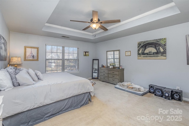 carpeted bedroom featuring a ceiling fan, a raised ceiling, visible vents, and crown molding