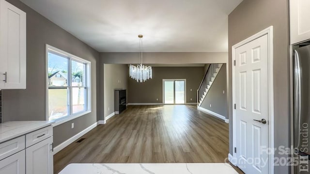 unfurnished dining area with an inviting chandelier, a healthy amount of sunlight, and light wood-type flooring